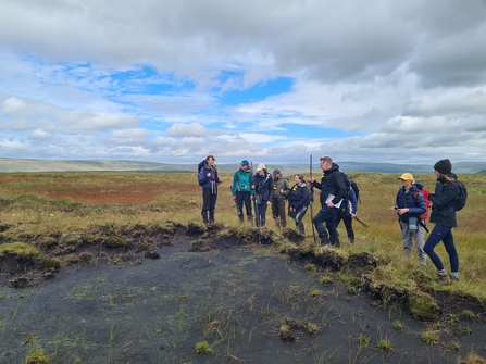 Peatland practitioner students receiving training next to a patch of bare peat in the Yorkshire Dales 