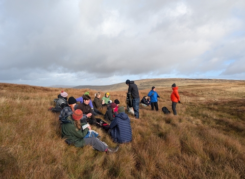 A group of young people sharing lunch on a peatland during the Peatland Pathways course